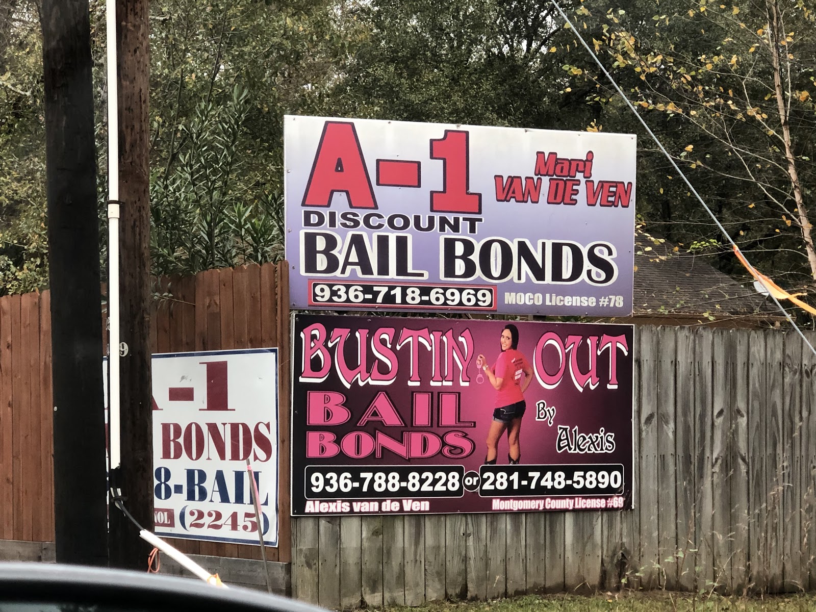 Two pink and red road signs read "A-1 Discount Bail Bonds" and "Bustin Out Bail Bonds"
