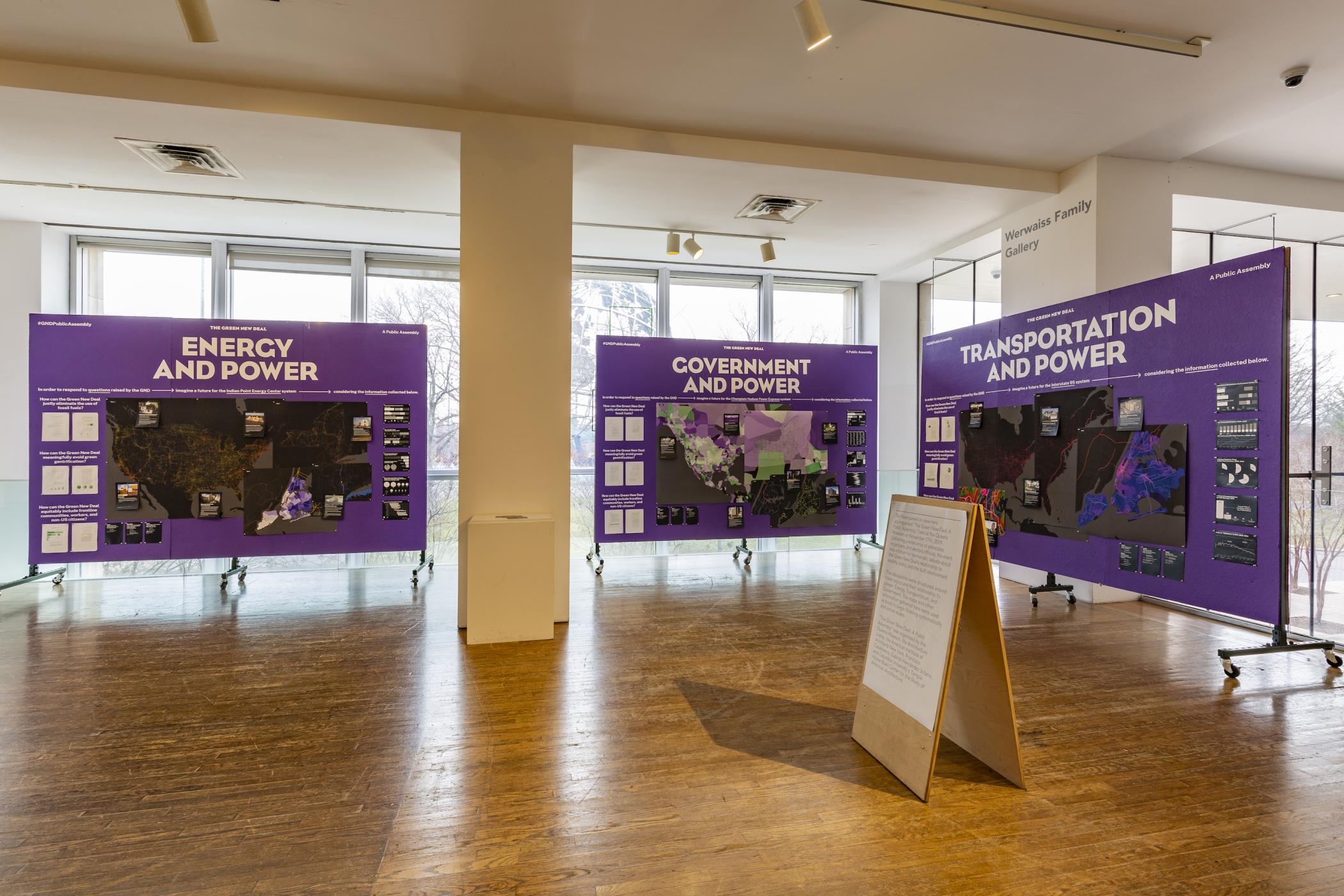Three purple large purple posters arranged in an L-shape display information under the headers "Energy and Power," "Government and Power," and "Transportation and Power"