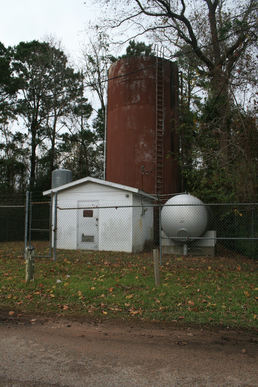 A small white pitched-roof building is shown in front of a red water tower.