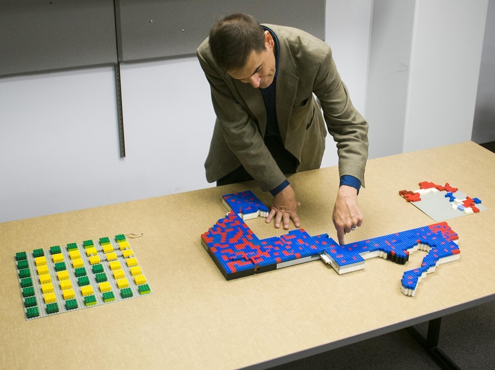 Wayne State University associate political science professor Kevin Deegan-Krause uses red and blue Legos to demonstrate gerrymandering on the map of Michigan. A zig-zag shape represents Michigan's 14th Congressional District.